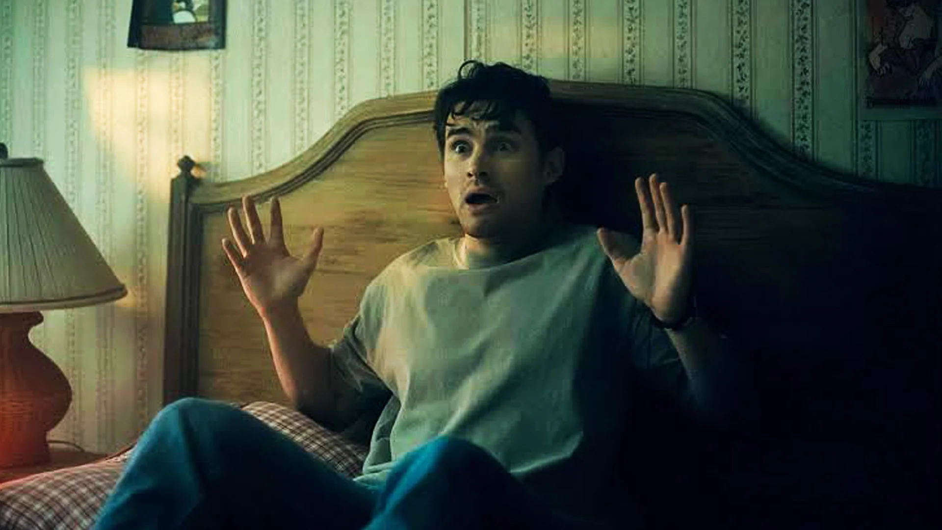 Man Sits Up in Bed with a Shocked Fearful Expression Hands Raised in Alarm in a Dimly Lit Bedroom