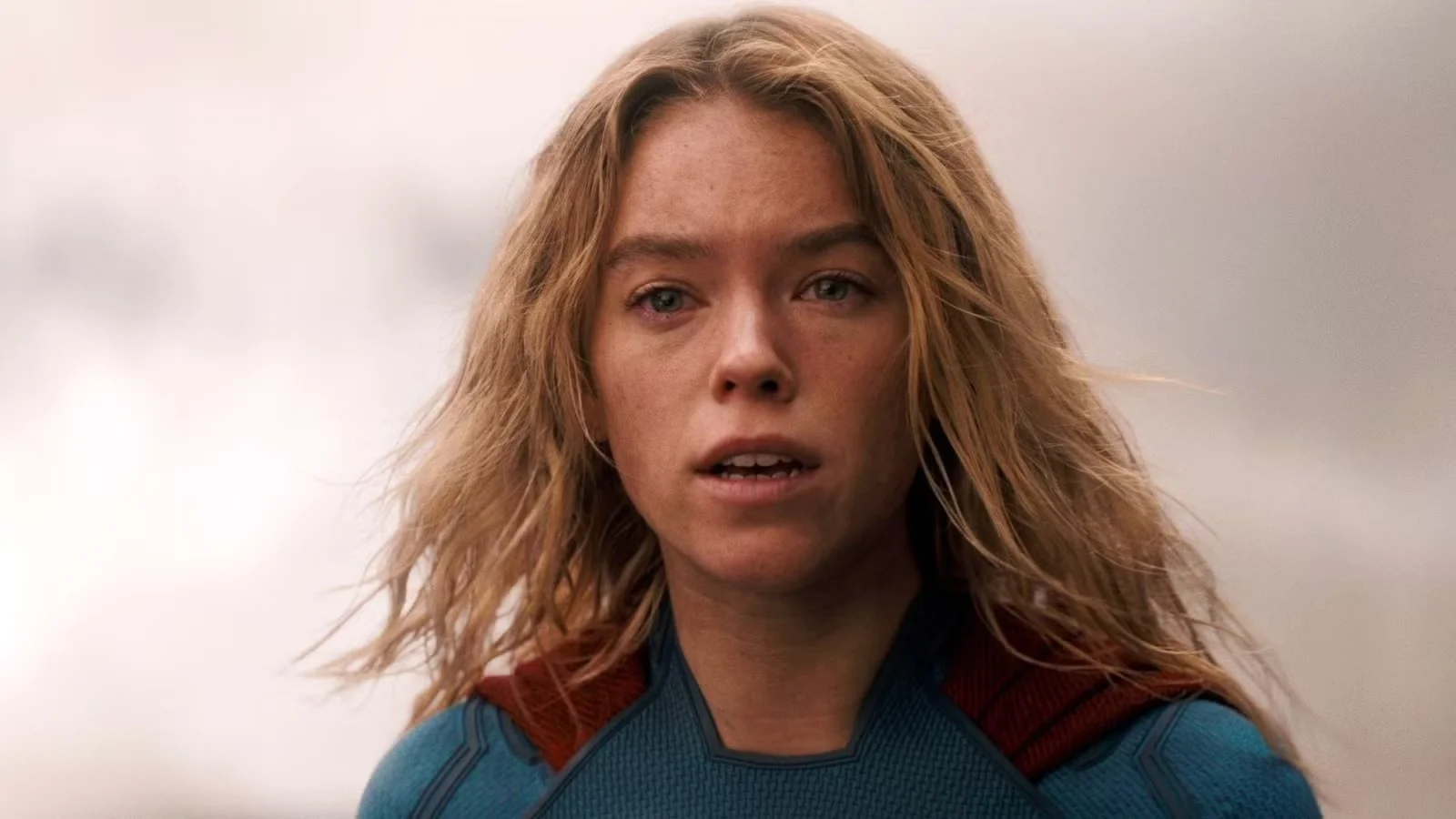 Supergirl Close up of a Blonde Woman in a Blue Superhero Suit with a Red Cape Looking Worried